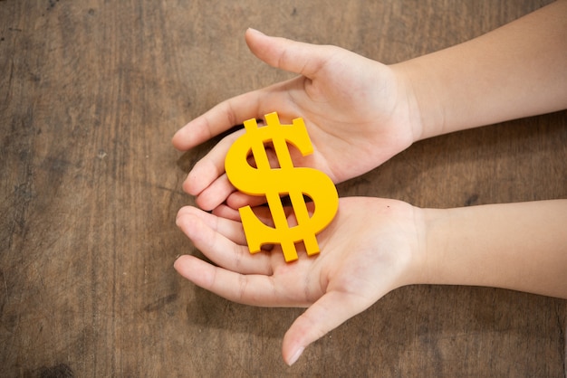 child holding yellow dollar sign 1150 18571 - Remittance Adalah Layanan Transfer Uang yang Menarik untuk Anda Coba