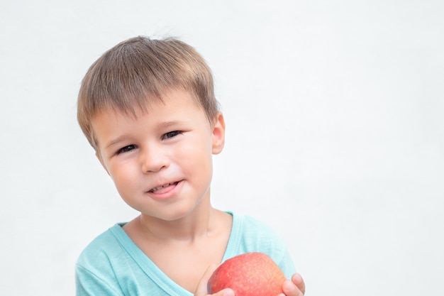 Premium Photo | The child is eating an apple on a gray background. boy ...