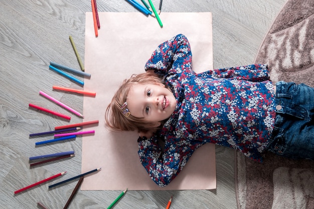 Premium Photo | Child lying on the floor on paper looking at the camera ...