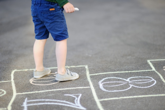 Child playing hopscotch game on playground outdoors on a sunny day Premium Photo