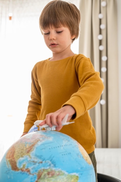 飛行機の置物と地球儀で遊ぶ子供 無料の写真