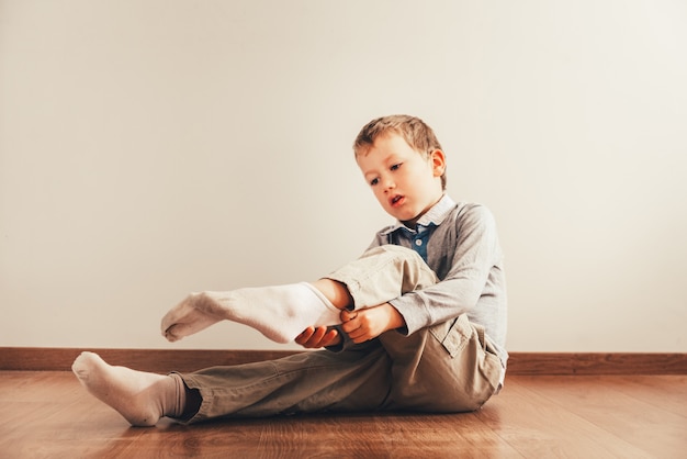 Premium Photo | Child sitting on the floor putting on his socks with an ...