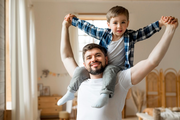 Child sitting on his father's shoulders | Free Photo