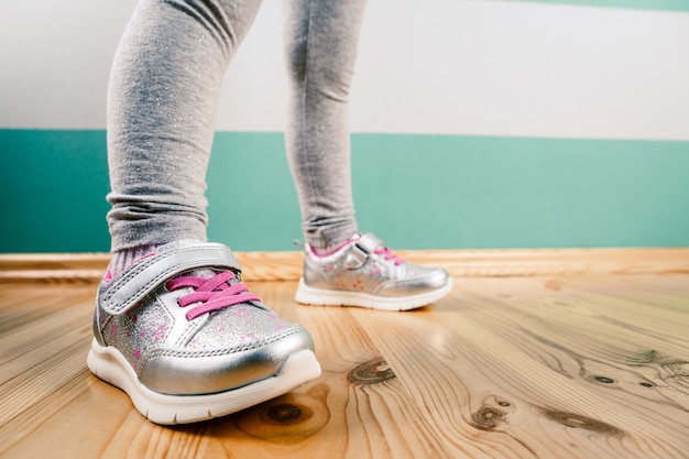 Child in sneakers on wooden surface