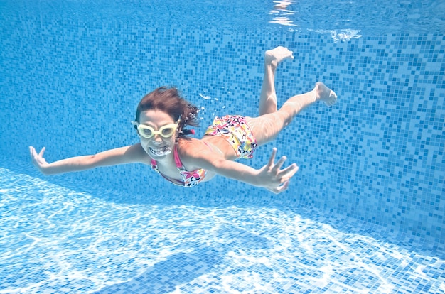 子供はプールのアクティブな女の子のダイビングで水中を泳ぎ 水中で子供たちのフィットネスを楽しんでいます プレミアム写真