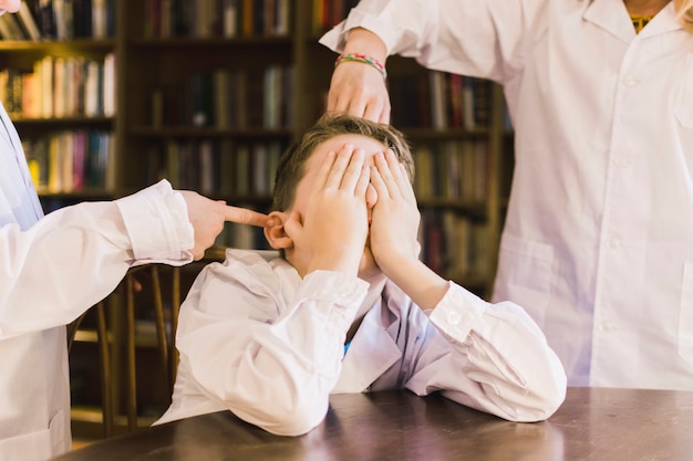 Children bullying little boy in library Free Photo