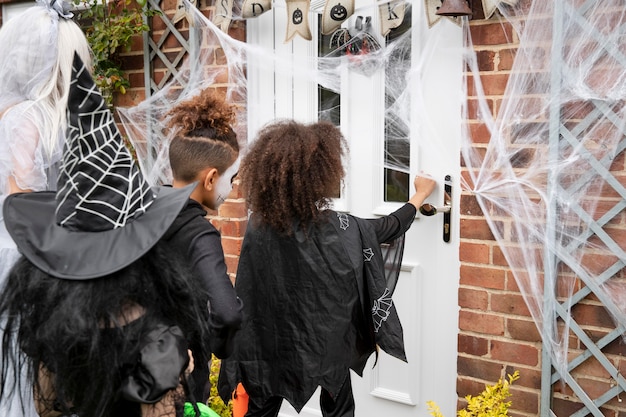 Children in costumes trick or treating at someone's house Free Photo
