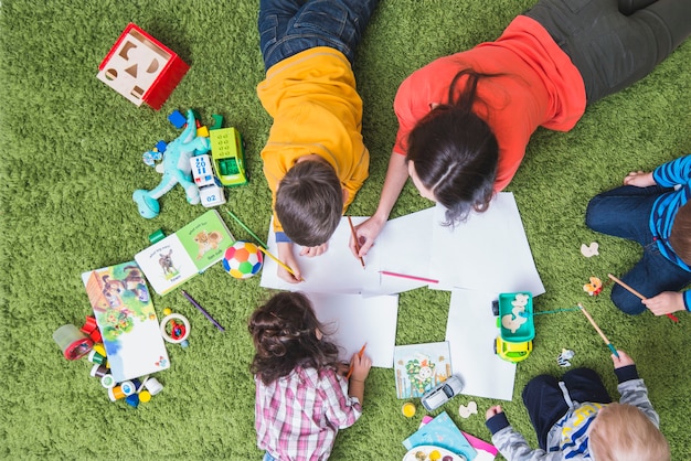 Children drawing and playing on carpet Free Photo