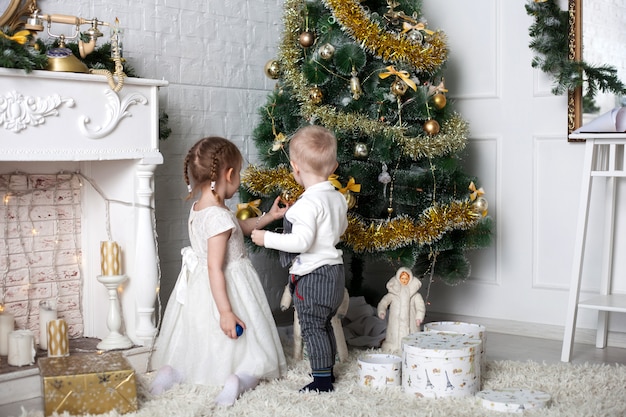 クリスマスツリー 男の子と女の子の近くの子供たちはクリスマスツリーをドレスアップ プレミアム写真