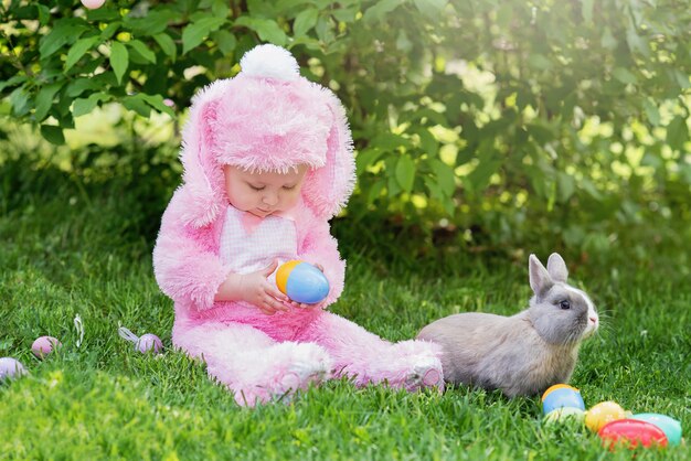 子供たちは本物のウサギと遊ぶ ペットのウサギとイースターエッグハントで子供を笑っています プレミアム写真