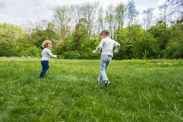 Premium Photo | Children playing on the green grass outdoor, runnig and ...