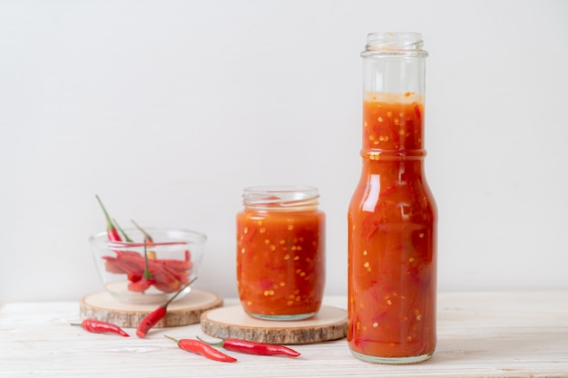 Premium Photo | Chilli or chilli sauce in bottle and jar on wood board