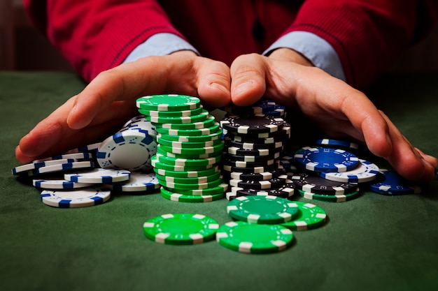 Chips in the foreground, in the blurring of the hands of a man holding chips , playing poker Premium Photo