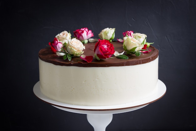 ビンテージスタンドにバラでチョコレートケーキ 赤と白のバラの花 黒の背景の美しいケーキ プレミアム写真