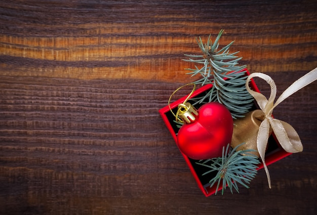 Christmas background: red gift box with a christmas toy in the shape of a heart, a golden bell ...