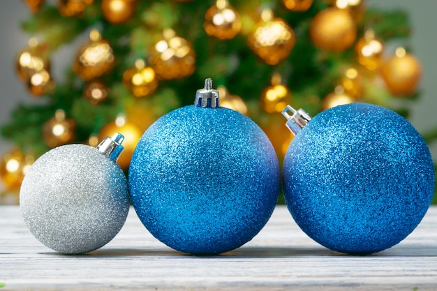 Christmas Baubles On Wooden Table Against Decorated Christmas Tree