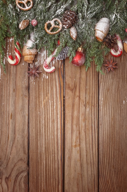 Christmas composition of tree branches, candies and decorations on wooden background. top view. copy space. Premium Photo