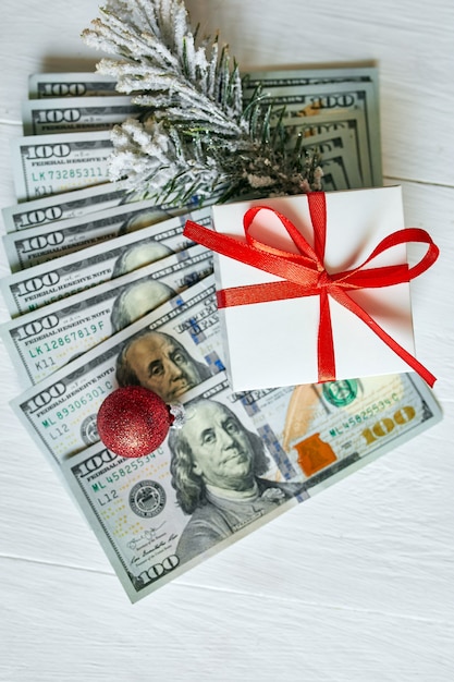 Premium Photo | Christmas gift box and us dollar bills on white wooden ...