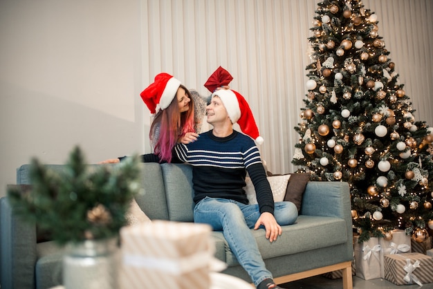 クリスマスプレゼント 家でクリスマスと新年の贈り物とサンタの帽子で幸せなカップル プレミアム写真