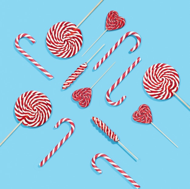 クリスマスの赤いキャンディケインと青い背景の上のロリポップパターン プレミアム写真