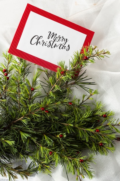 クリスマスカードモックアップと白い布のクリスマスツリーの枝 無料の写真