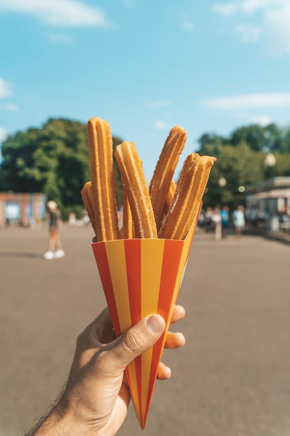 Premium Photo | Churros Waffles In Hand On The Street Churros Street ...