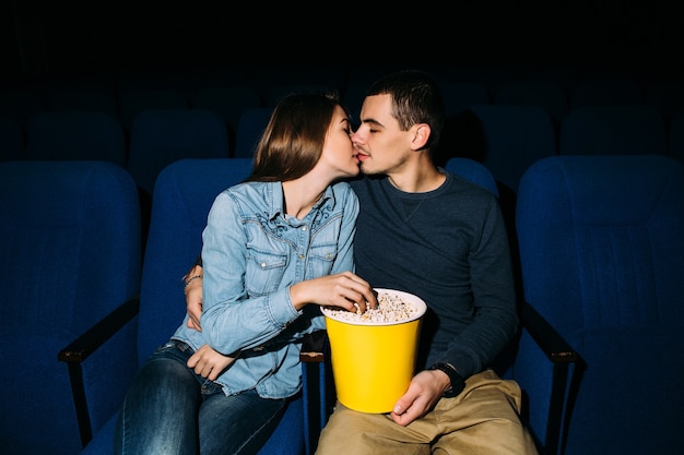 映画館の日 映画館でロマンチックな映画を見ながらキスしている若い美しいカップル 無料の写真