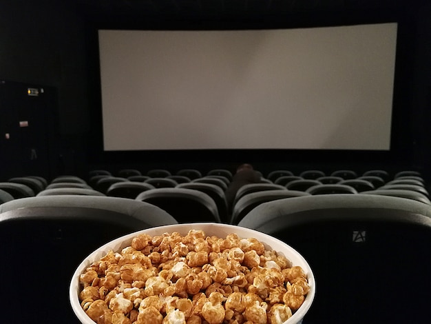 Premium Photo | Cinema seat and pop corn facing empty movie screen