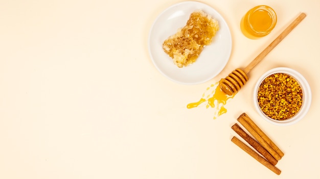 Cinnamon stick; honeycomb; jar of honey and bee pollen with copy space backdrop Free Photo
