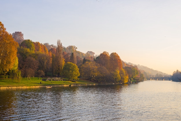 City view of torino (turin - italy) at sunset in autumn season with church on hilltop overlooking po river and colorful trees. Premium Photo