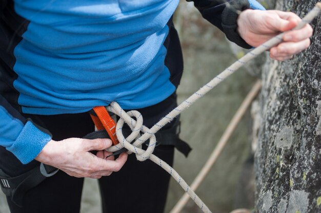 Premium Photo | Climber woman in safety harness tying rope in bowline knot