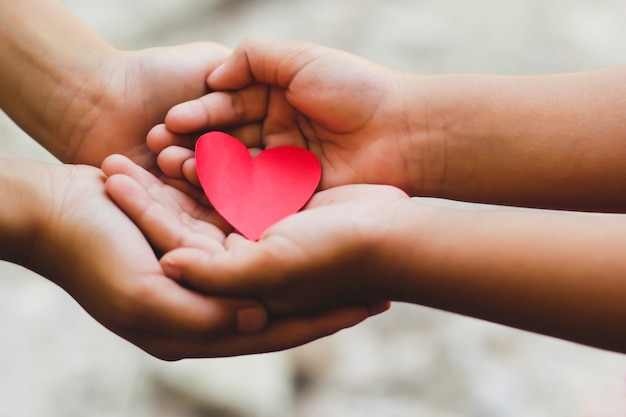 Premium Photo | Close up of adult and child hands holding red heart.