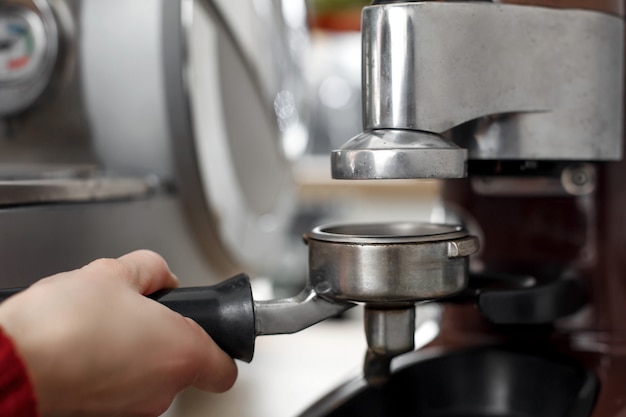 Close-up of a barista hand picking up ground coffee in a holder for cooking in a coffee machine Premium Photo