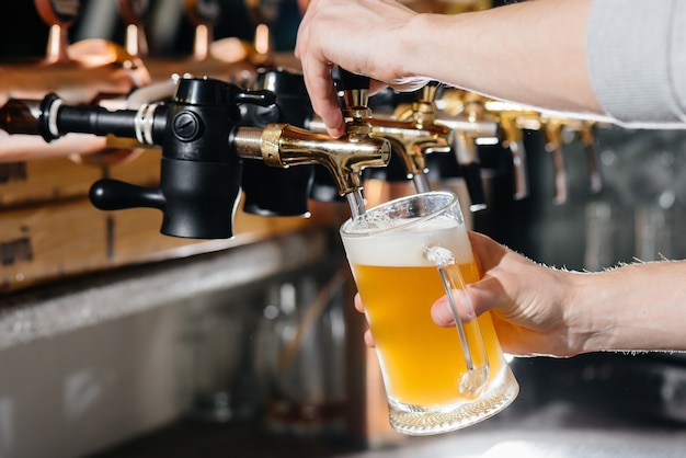 Premium Photo | Close-up of the bartender filling a mug of light beer ...