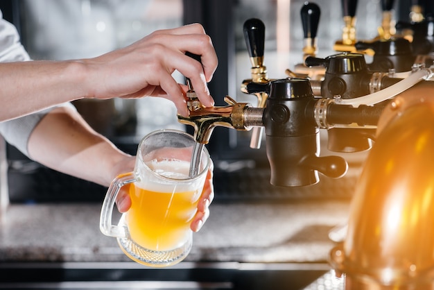 Premium Photo | Close-up of the bartender filling a mug of light beer ...