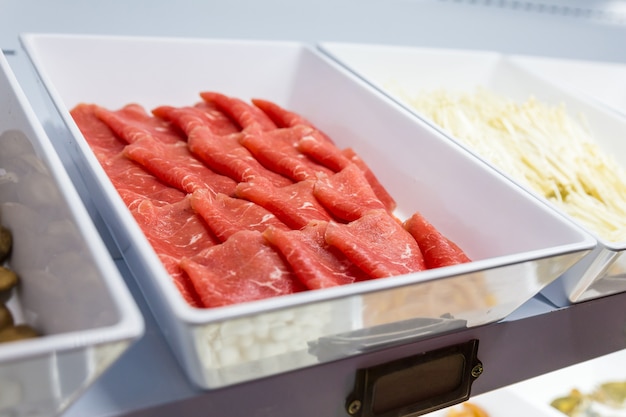Close up beef inside fresh foods line for sukiyaki buffet in refrigerator. Premium Photo