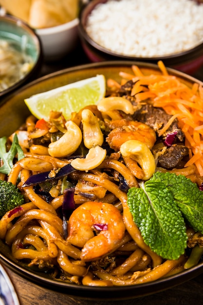 Close-up bowl of udon noodles with nuts; lemon slice; mint and beefs Free Photo