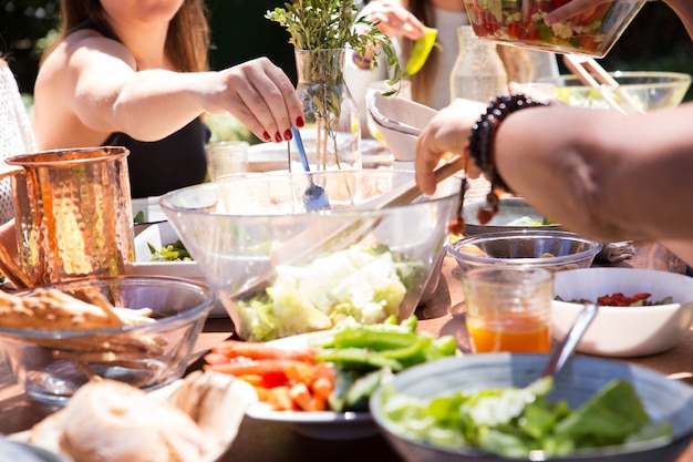 Close-up of bowls and plates with food and female hand with fork Free Photo