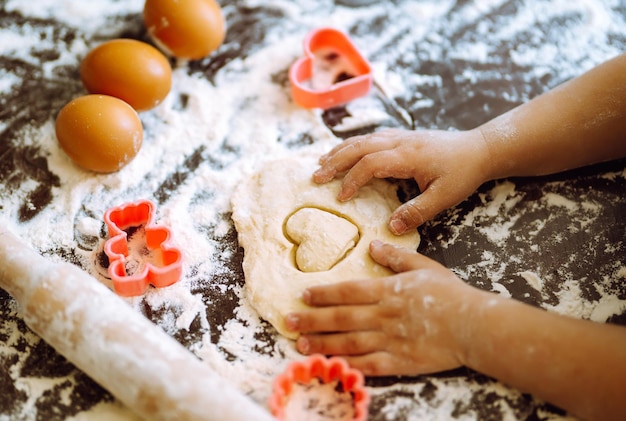 Premium Photo | Close up of boy hands carving dough with cookie heart ...