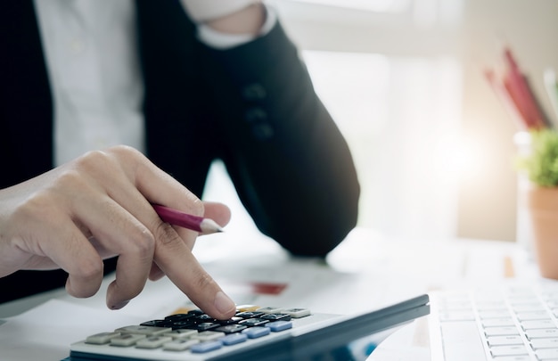 Close up business woman using calculator and laptop for do math finance on wooden desk in office and business working, tax, accounting, statistics and analytic research concept Premium Photo