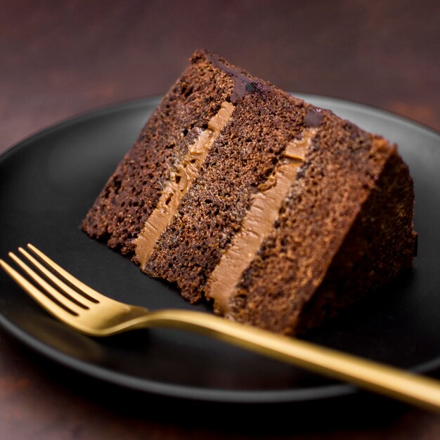 Close-up of cake slice on plate with golden fork | Free Photo