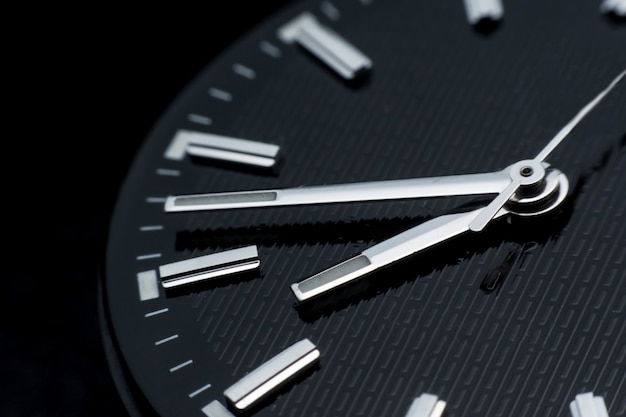 黒い時計の文字盤の背景に時計回りにクローズアップ レトロなスタイルの腕時計 プレミアム写真