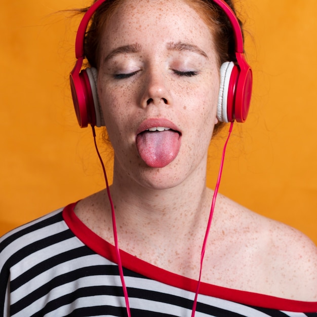 舌出しとヘッドフォンでクローズアップかわいい女性 無料の写真