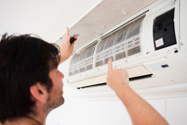 Close-up of electrician repairing air conditioner Free Photo