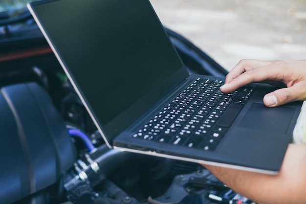 Close up engineer mechanic using electrnoic diagnostic equipment to tune a car Premium Photo