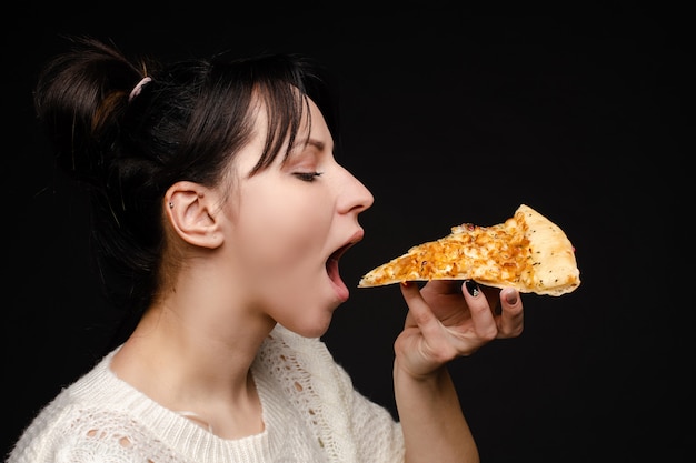 空腹の若い女性のクローズアップ顔は ピザの食欲をそそる食欲をそそる口を開けて準備ができて プレミアム写真