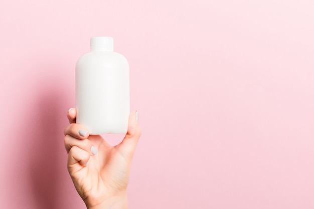 Premium Photo | Close up of female hand holding cosmetics bottle at pink