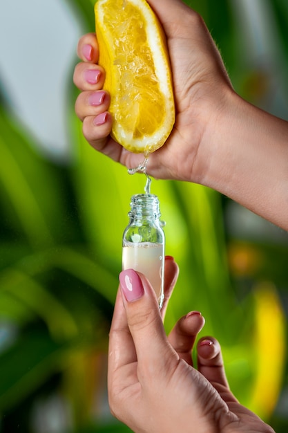Close-up: a female hand squeezes juice from a lemon into a glass bottle. the  of natural cosmetics P