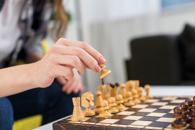 Close-up of female's hand playing the wooden chessboard Free Photo