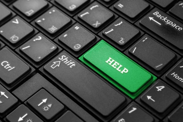 Close up green button with word help, on black keyboard. creative background, copy space. the concept of quick help, magic button, mutual assistance. Premium Photo